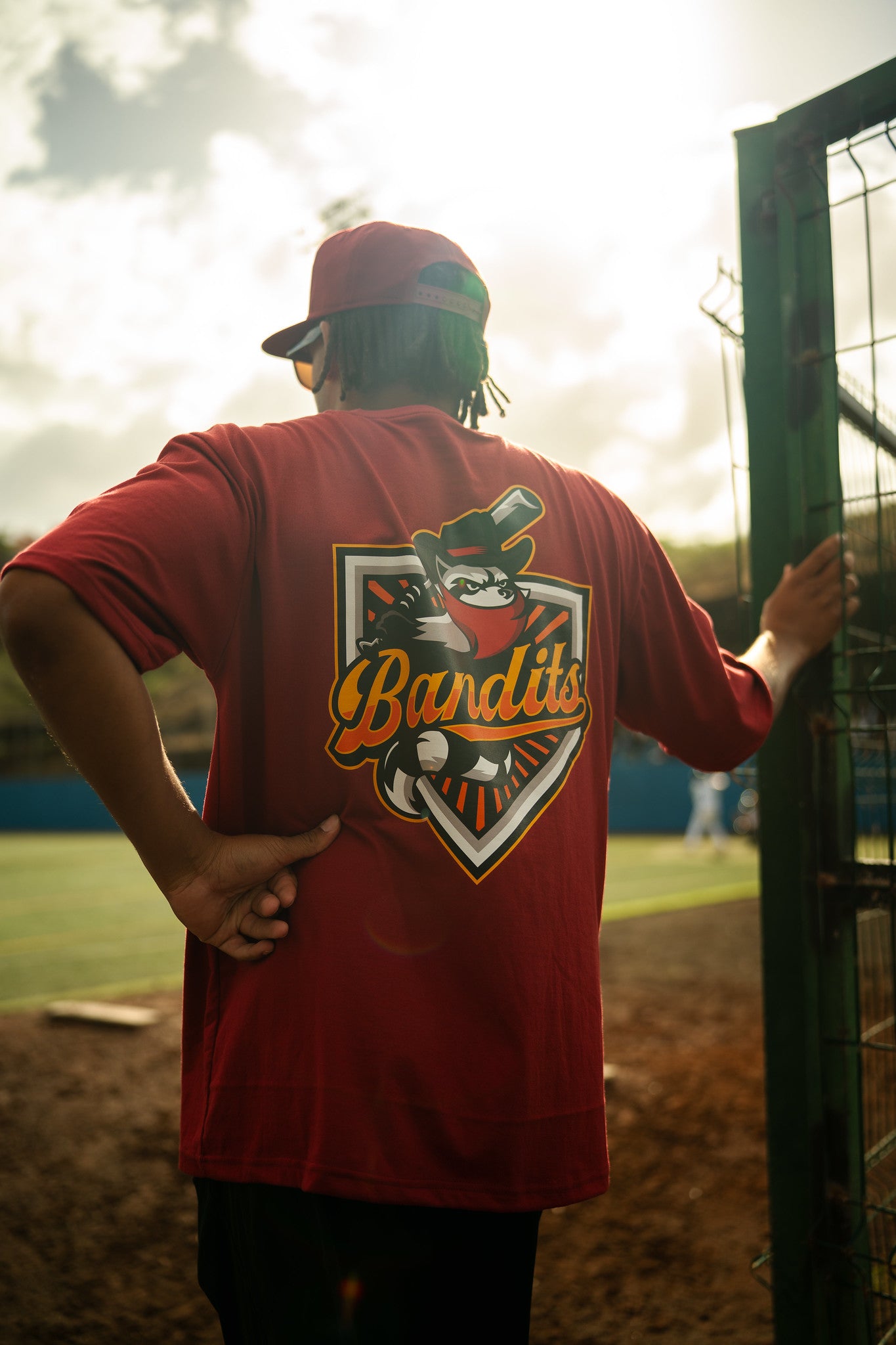 Trainer steht mit dem Rücken zur Kamera am Spielfeldrand, Teamlogo auf dem Shirt sichtbar
