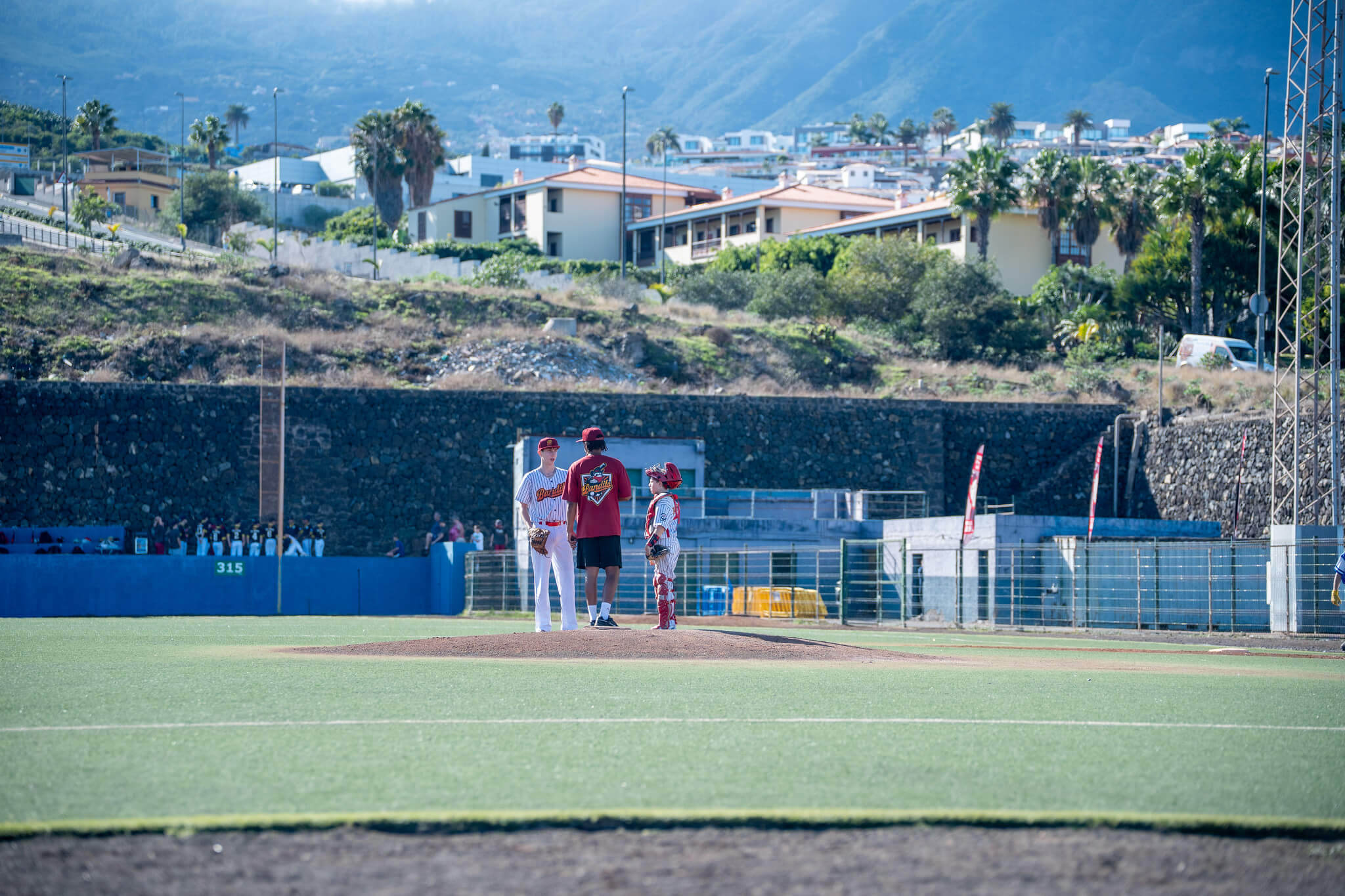 Coach spricht mit U15-Baseballspielern am Pitching Mound während eines Spiels