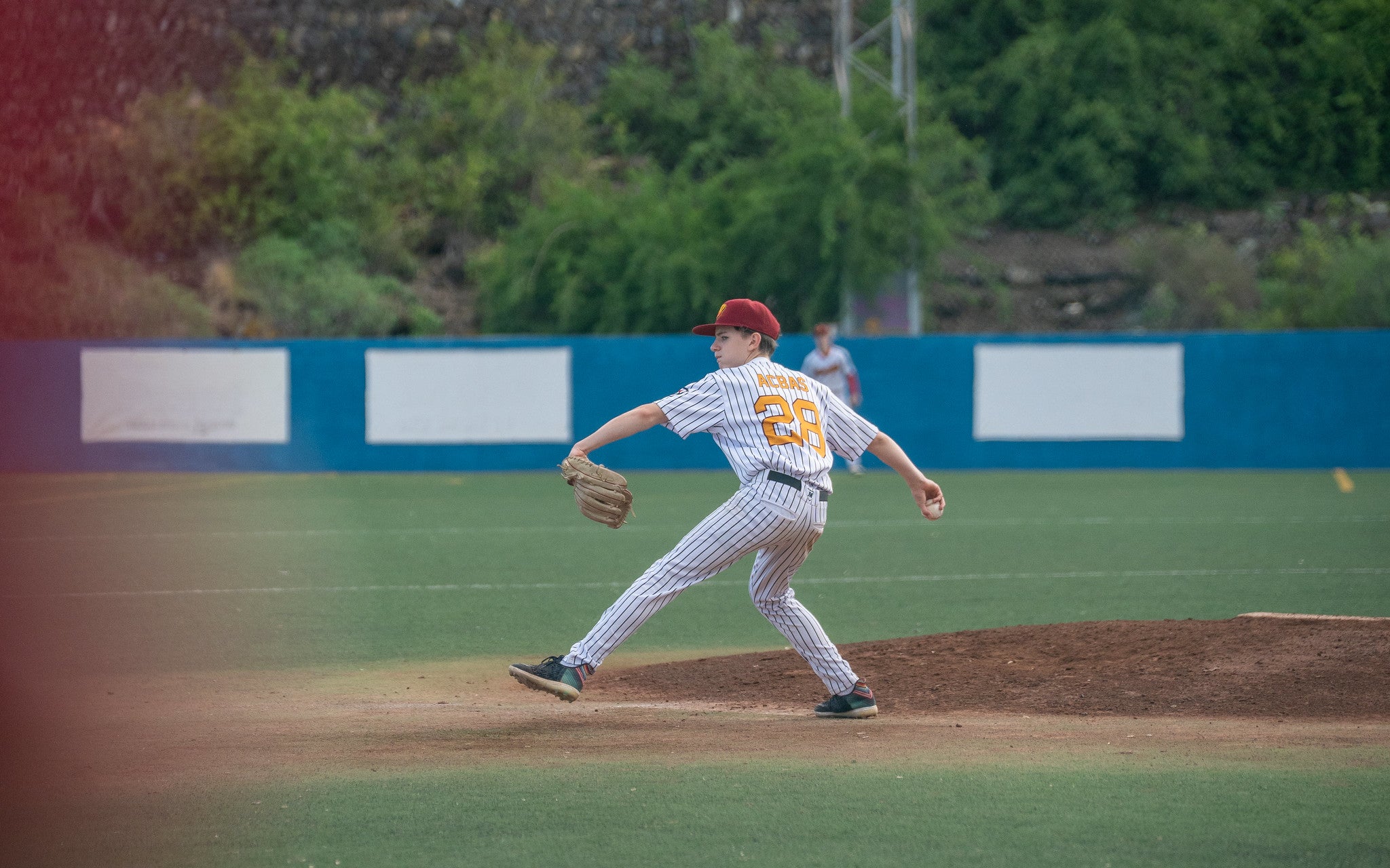 U15-Baseballspieler wirft als Pitcher den Ball vom Mound während eines Spiels