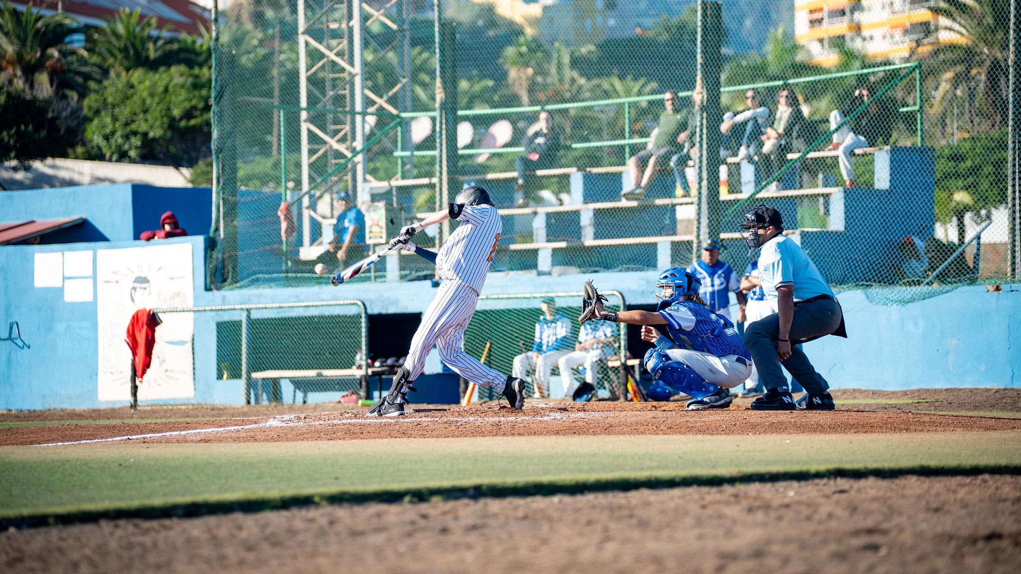 U15-Baseballspieler schlägt den Ball, Catcher und Schiedsrichter im Hintergrund